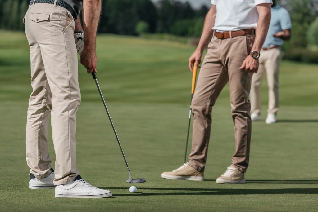 cropped shot of sportsmen playing golf together on golf course at daytime